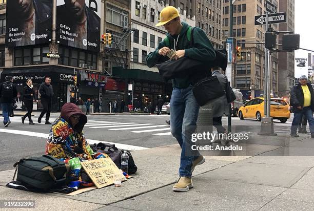Homeless person with his belongings tries to stay warm on a street while panhandling during freezing temperatures at the 5th Avenue in New York,...