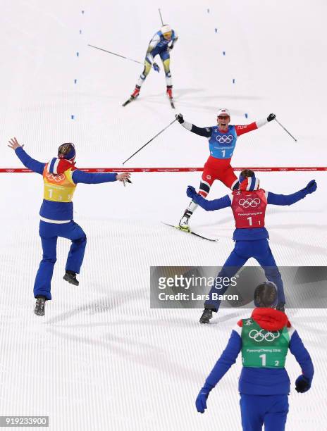 Marit Bjoergen of Norway celebrates with team mates as she crosses the finish line to win gold ahead of Stina Nilsson of Sweden during the Ladies'...
