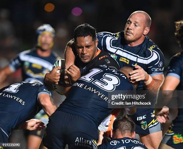 Felise of the Tigers is tackled by Matthew Scott and John Asiata of the Cowboys during the NRL trial match between the North Queensland Cowboys and...