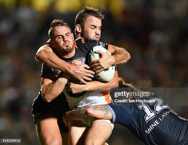 Josh Reynolds of the Tigers is tackled by Sam Hoare and Ethan Lowe of the Cowboys during the NRL trial match between the North Queensland Cowboys and...