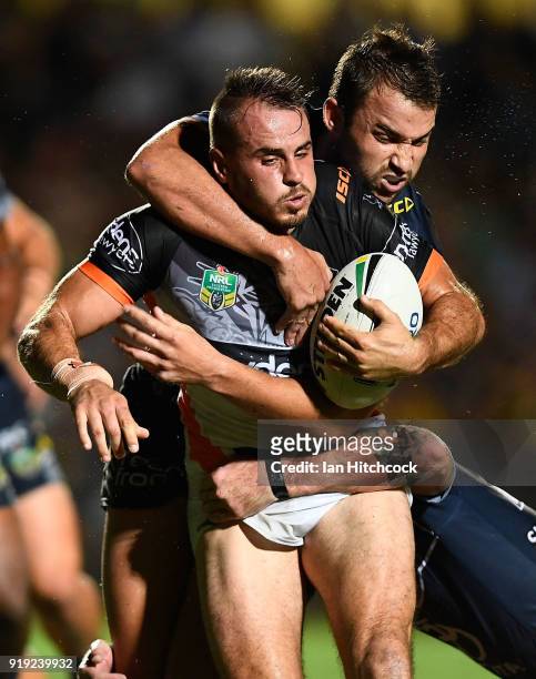 Josh Reynolds of the Tigers is tackled by Sam Hoare and Ethan Lowe of the Cowboys during the NRL trial match between the North Queensland Cowboys and...