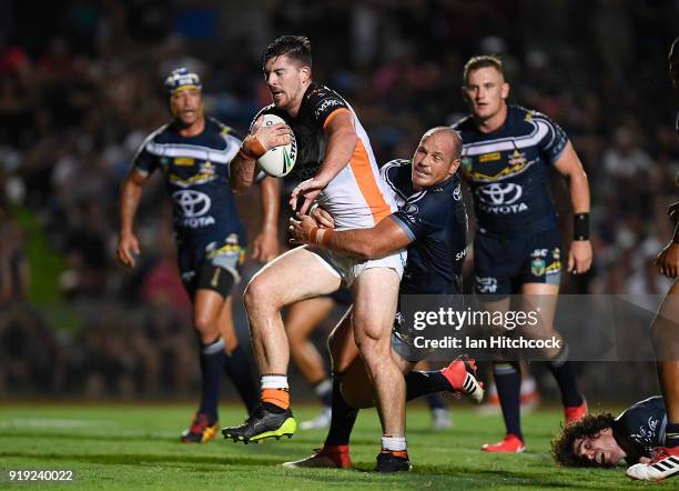 Matt Eisenhuth of the Tigers is tackled by Matt Scott of the Cowboys during the NRL trial match between the North Queensland Cowboys and the Wests...