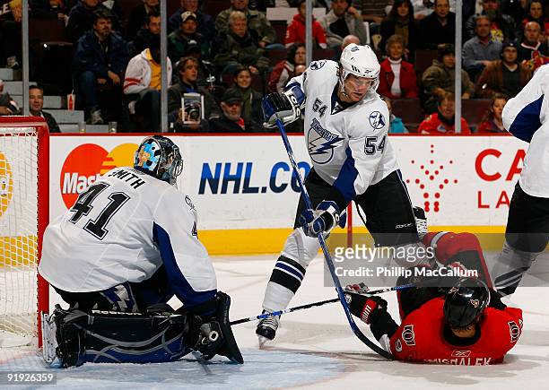 Milan Michalek of the Ottawa Senators is knocked to the ice by Paul Ranger of the Tampa Bay Lightning out front of his goalie Mike Smith during a...
