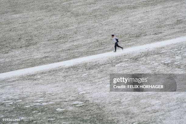 Man jogs through the snow covered Englischer Garten park in Munich, southern Germany, on February 17, 2018. / AFP PHOTO / dpa / Felix Hörhager /...