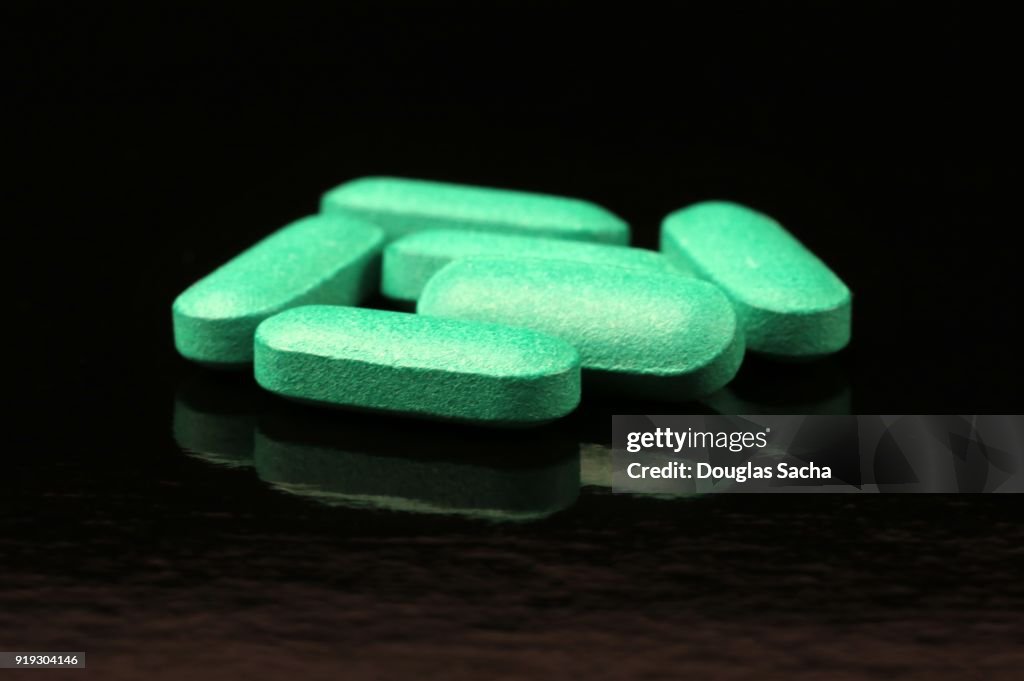 Green pills on a black background