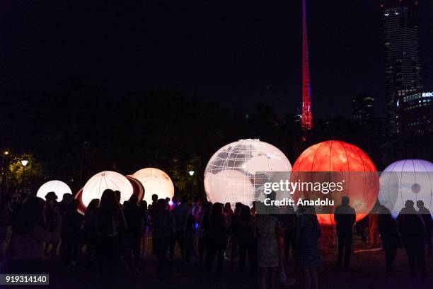 People stand in front of the La Terra Al Centro Dell Universo, a large scale representation of the galaxy during the White Night Melbourne festival...