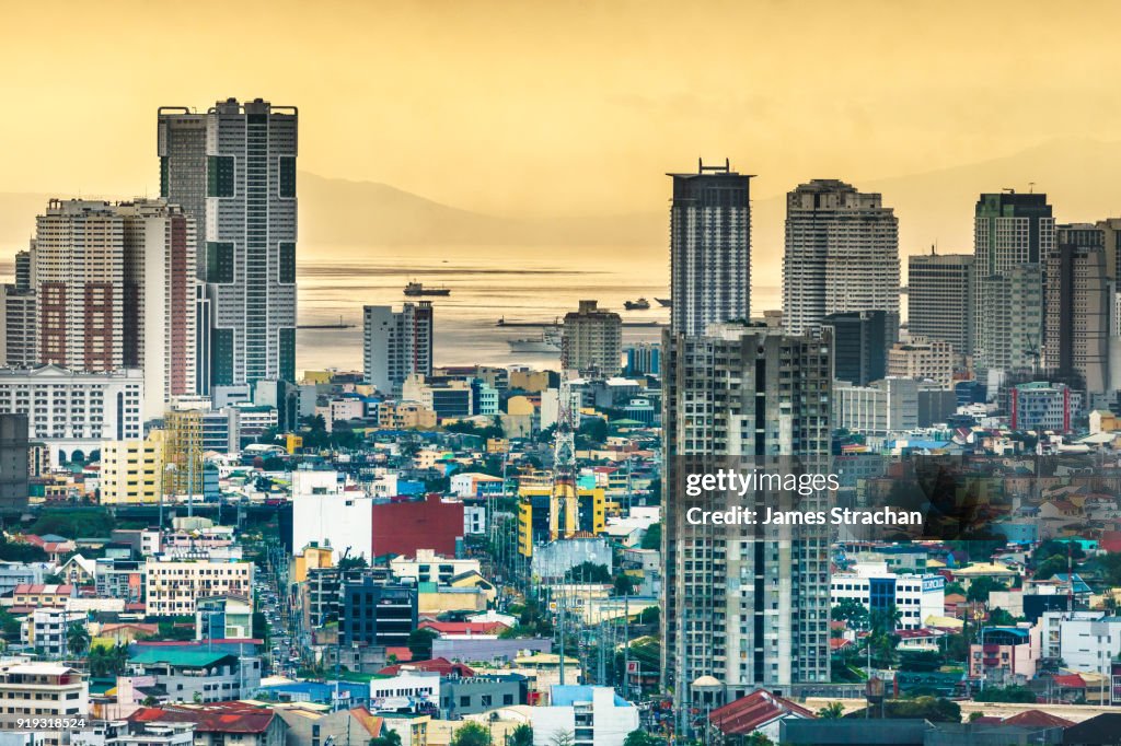 Aerial cityscape at dusk (sulphurous sky from recent volcanic eruptions) with the port in the distance, Manila, Philippines