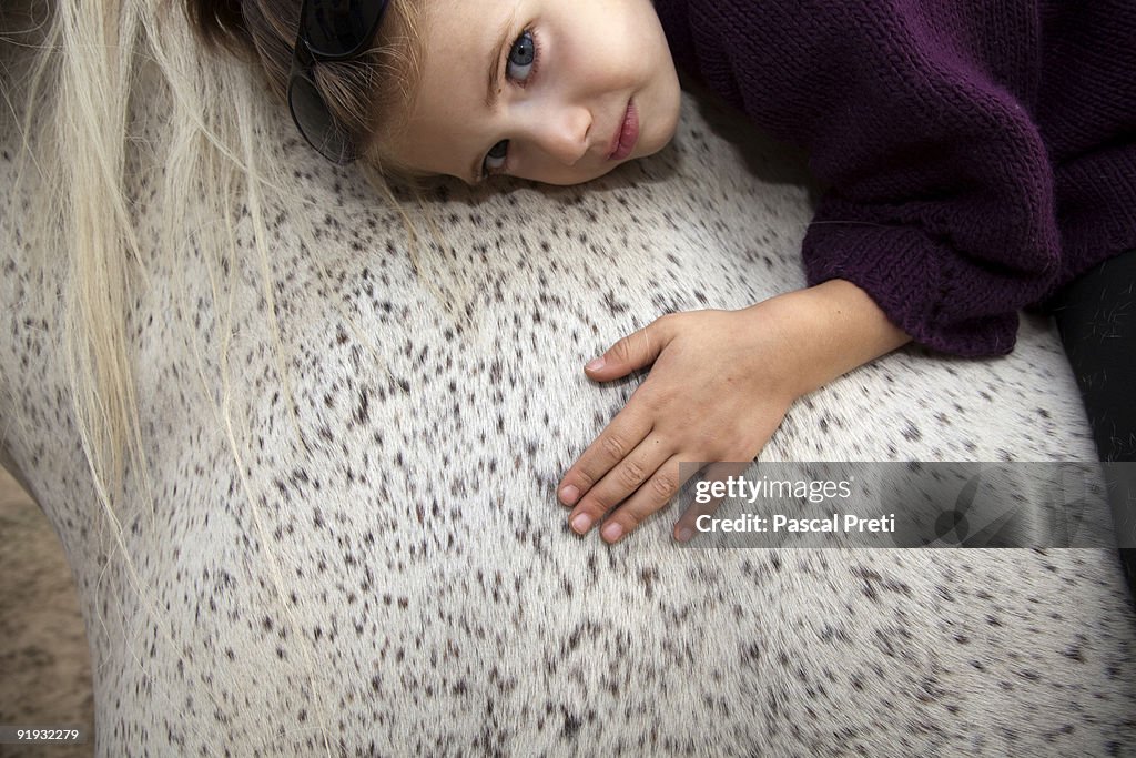 Close up of young girl lying on a horse