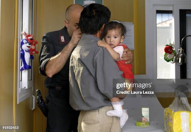 An Italian Carabiniere doctor treats an Afghan child on his father's arms at Italian PRT on September 19, 2009 in Herat, Afghanistan. The Italian PRT...