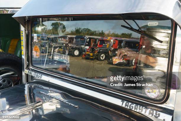 reflection in the front window of a jeepney, the most popular means of public transport in the philippines, as the driver takes money and prepares to leave the jeepney terminal. their kitsch decorations are a ubiquitous symbol of popular art, tagaytay, lu - tagaytay stock pictures, royalty-free photos & images