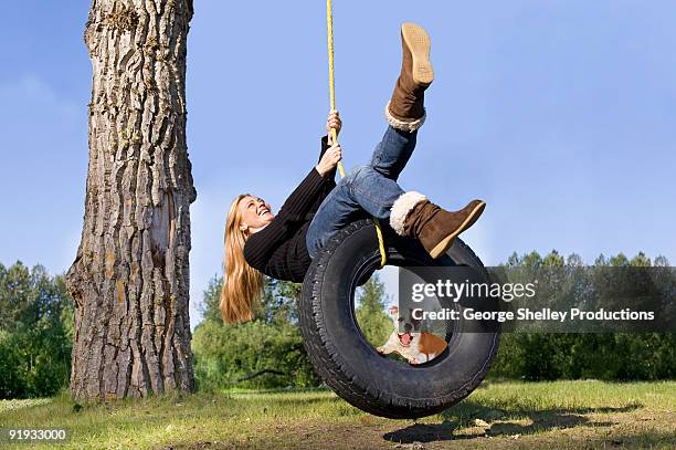 smiling girl on tire swing with a puppy - schaukel stock-fotos und bilder