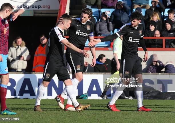 Chris Long of Northampton Town is congtatulated by team mates Ash Taylor and Brendan Moloney during the Sky Bet League One match between Scunthorpe...