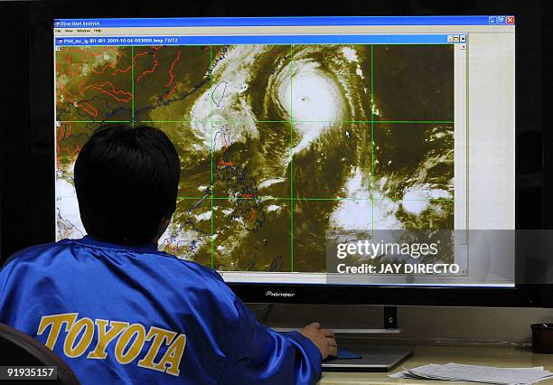 By Cecil Morella A meteorologist of the Philippines government weather service monitors the course of tropical storm Parma and Typhoon Melor through...