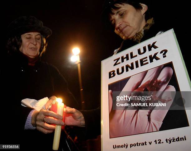 Catholics march with candles and posters with a picture of 11 week human aborted foetus in a human hand near the stone monument for unborn children...