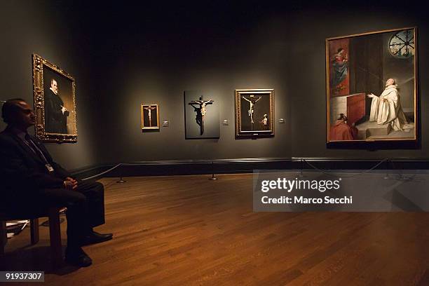 National Gallery employee seats next to three paintings of Crucifixion by Francisco Paceco, Juan de Mesa and Francisco de Zurbaran at 'The Sacred...