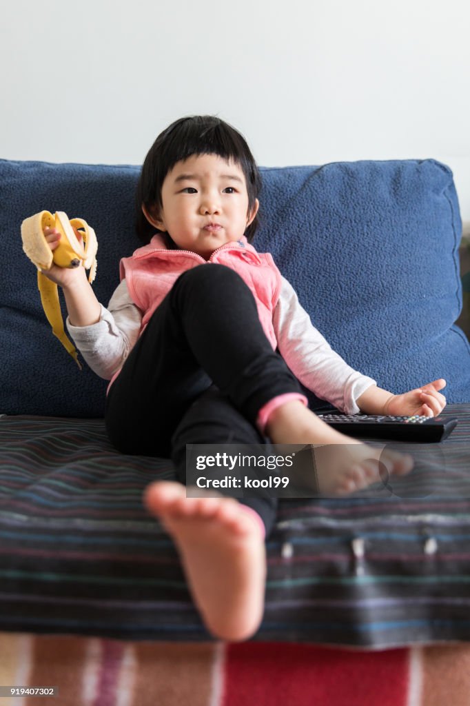 Resting at home kid eating bananas and watching TV