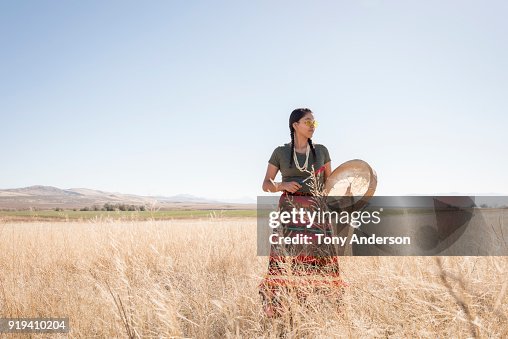 Young Native American woman with drum in open field Young Native American woman with drum in open field