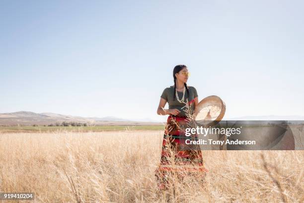 young native american woman with drum in open field - native american reservation stockfoto's en -beelden