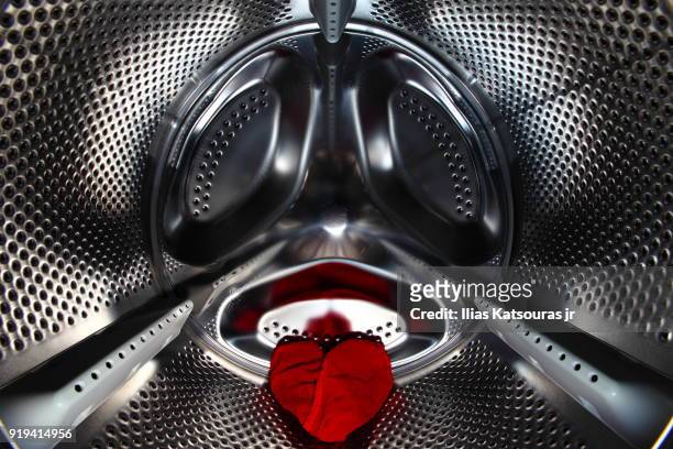 red underwear in the shape of a heart in washing machine drum, laundry - katsouras stock-fotos und bilder