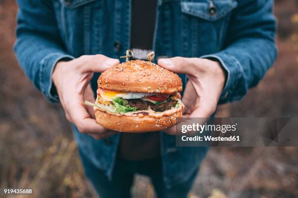 hand holding burger - man holding a burger stock pictures, royalty-free photos & images