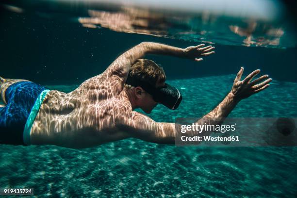 man diving in a swimming pool wearing vr glasses - virtual vacations stock pictures, royalty-free photos & images