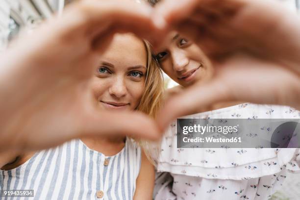 two smiling young women shaping heart with their hands - molding a shape stock pictures, royalty-free photos & images