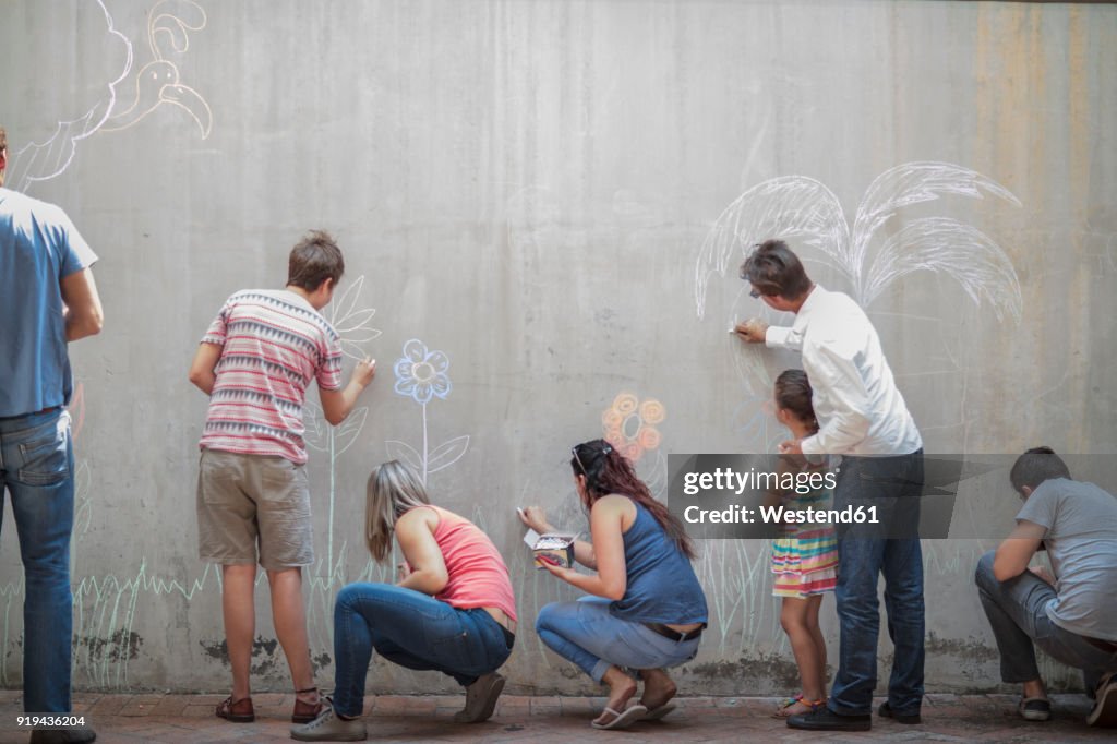 People drawing colourful pictures with chalk on a concrete wall