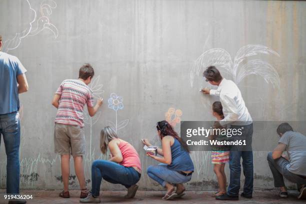 people drawing colourful pictures with chalk on a concrete wall - drawing activity stock pictures, royalty-free photos & images