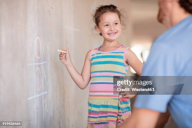 father and daughter playing tic tac toe with chalk on a concrete wall - tic tac toe photos et images de collection