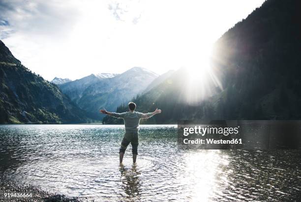 austria, tyrol, hiker standing with outstretched arms in mountain lake - meta turistica fotografías e imágenes de stock