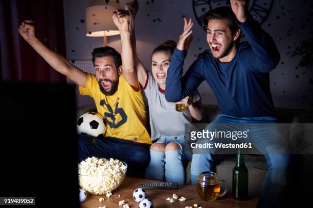 excited friends sitting on the sofa watching tv - fan enthusiast stock pictures, royalty-free photos & images