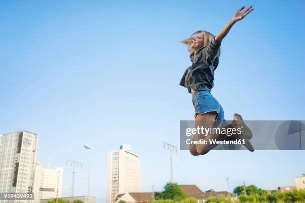 happy young woman jumping in the air - women in daisy dukes stockfoto's en -beelden