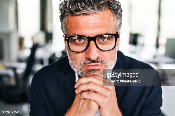 portrait of serious mature businessman wearing glasses in office - guy with face in hands stockfoto's en -beelden