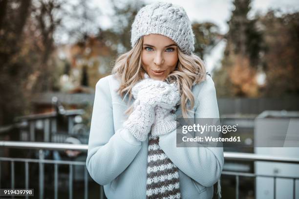portrait of smiling woman wearing woolly hat, gloves and scarf - cold temperature stock-fotos und bilder