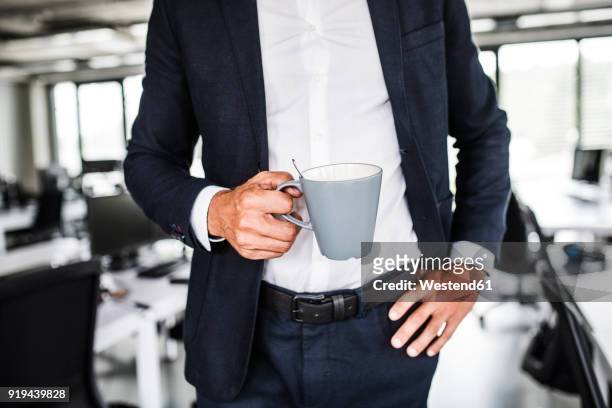 close-up of businessman holding coffee mug in office - mug photos et images de collection