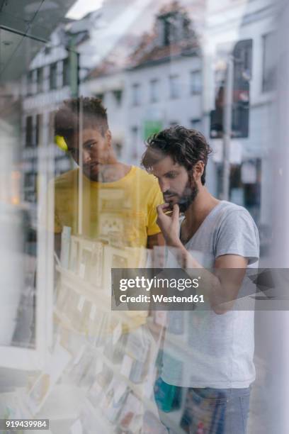 two friends in the city looking in shop window of a bookstore - effet miroir homme photos et images de collection