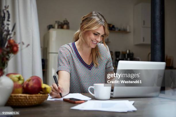 portrait of laughing woman working on laptop at home - frau offenes lächeln küche stock-fotos und bilder