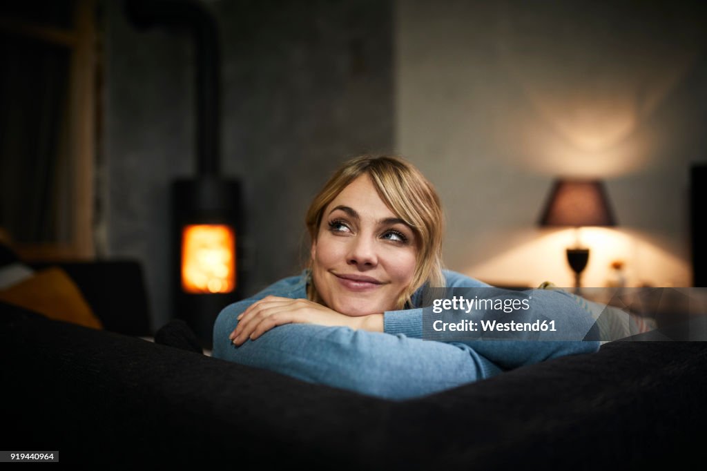Portrait of smiling woman relaxing on couch at home in the evening