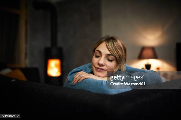 portrait of woman relaxing on couch at home in the evening - low key beleuchtung stock-fotos und bilder