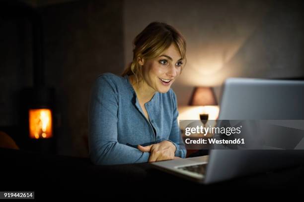portrait of amazed woman using laptop at home in the evening - starren stock-fotos und bilder