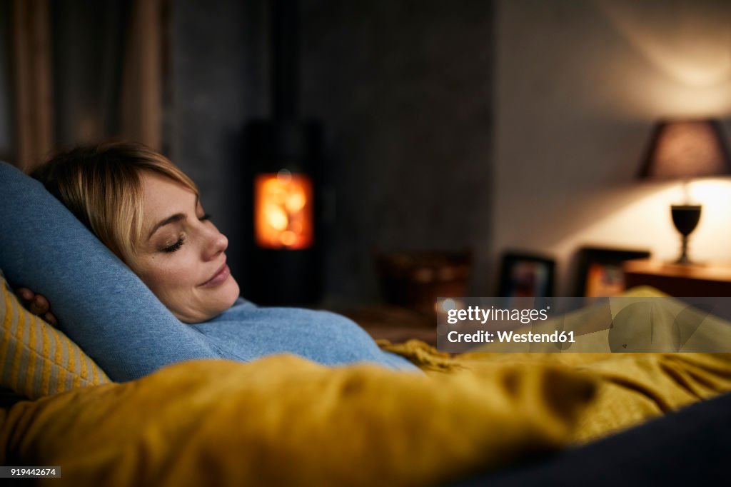Portrait of smiling woman relaxing on couch at home in the evening
