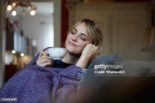 portrait of smiling woman with cup of tea relaxing on couch at home - comfortable 個照片及圖片檔