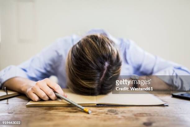 close-up of woman lying on notebook at desk - burnout fotografías e imágenes de stock