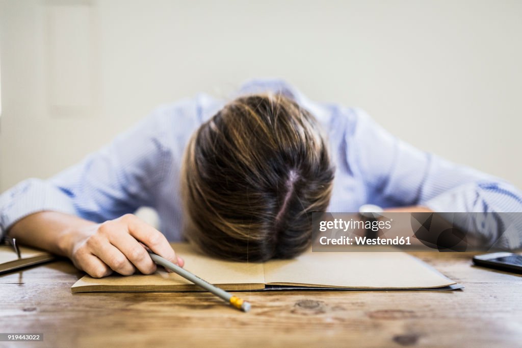 Close-up of woman lying on notebook at desk