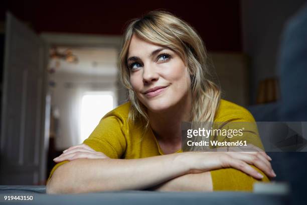 portrait of woman lying on the couch at home thinking - hoffnung stock-fotos und bilder