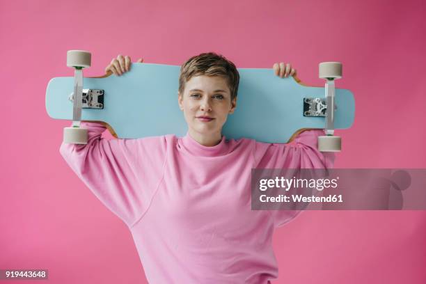 portrait of woman in pink holding skateboard - ボード　持つ　女性 ストックフォトと画像