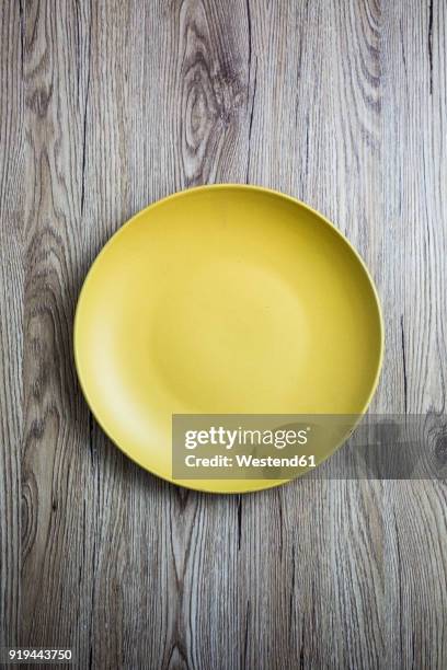 empty yellow plate on wood - plate stock-fotos und bilder