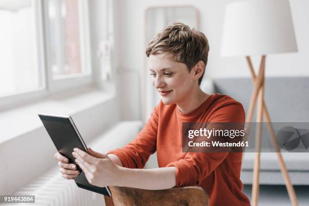 smiling woman sitting on chair using tablet - sitting chair office relax stock pictures, royalty-free photos & images