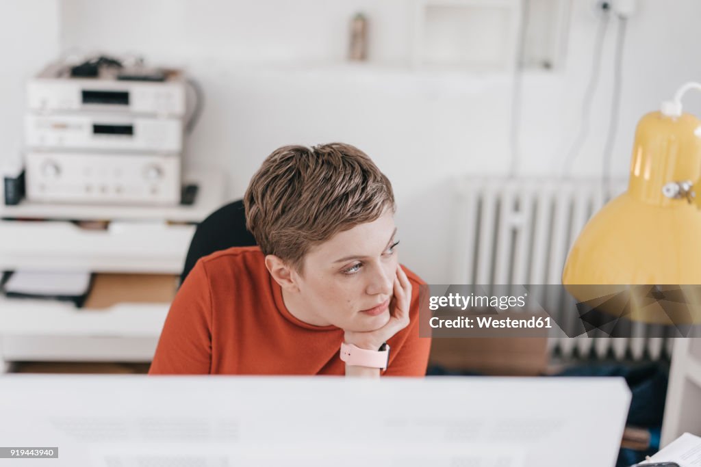 Woman at desk in office thinking
