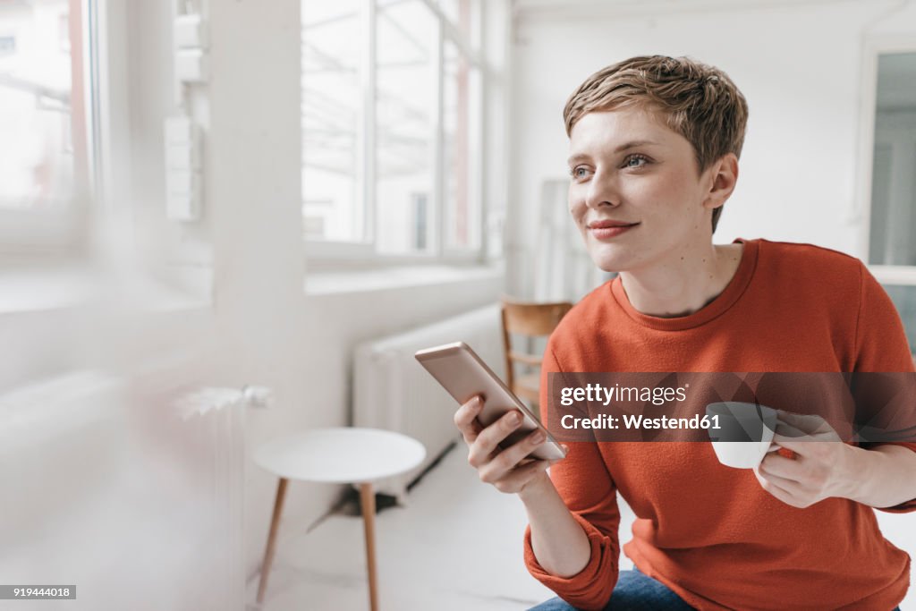 Smiling woman with cell phone and espresso cup